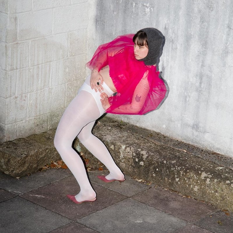 Fashion photograph of a woman in white tights and a pink top doing a back bend