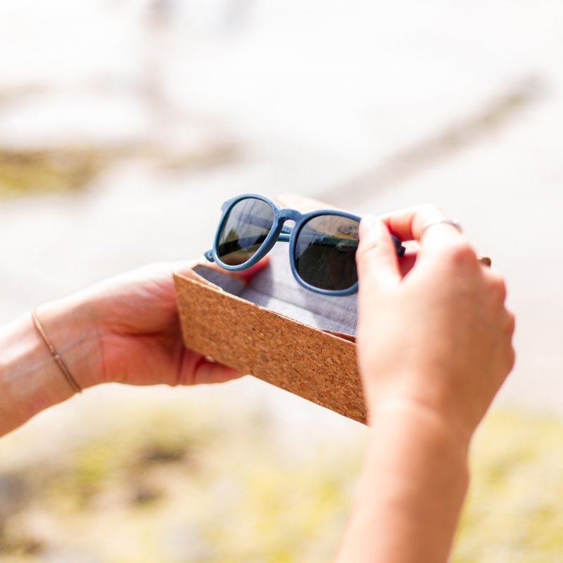 A pair of sunglasses are removed from a bamboo box