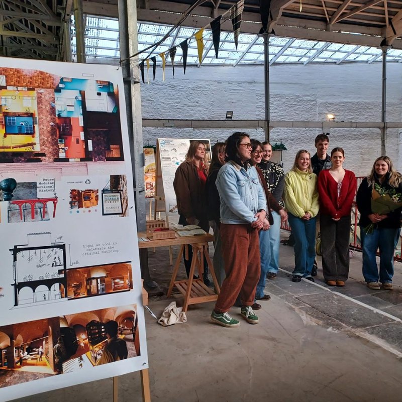 A group of interior architecture students next to their exhibition at market house