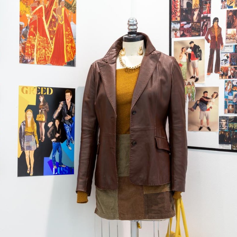 Mannequin wearing a brown leather jacket, skirt and orange top