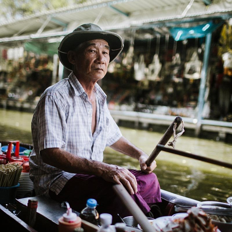 Asian food vendor on boat with food, chopsticks and sauces.