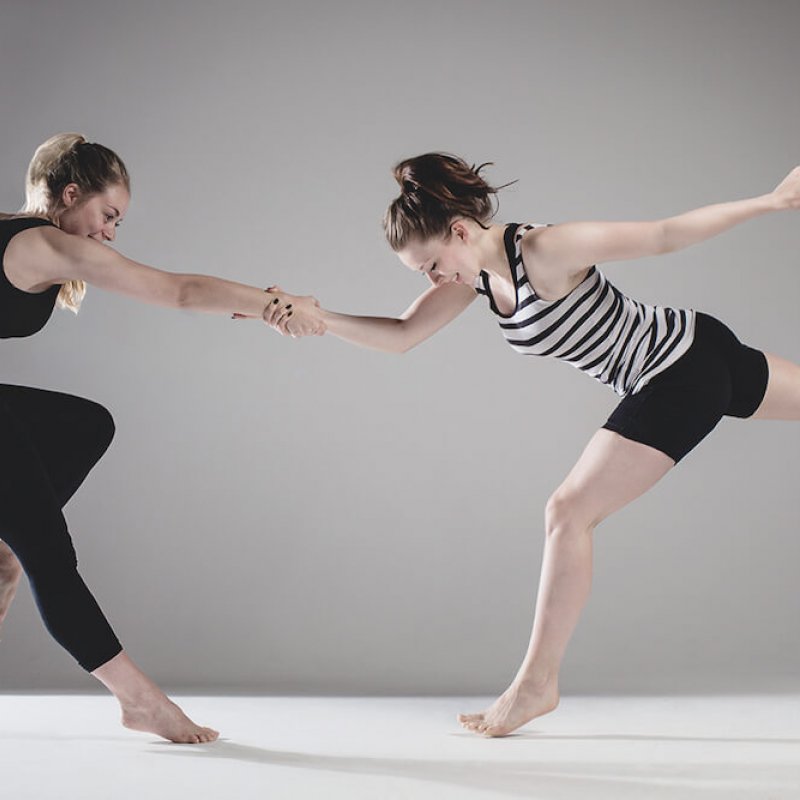 Two dancers in handshake hold and one leg extended and one leg bent