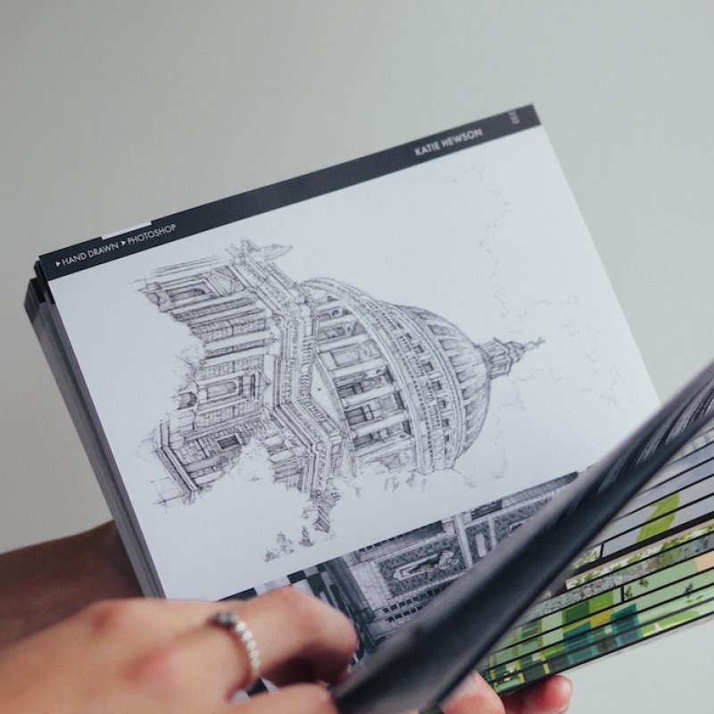 Hands opening the inside of a book with a drawing of St Paul's