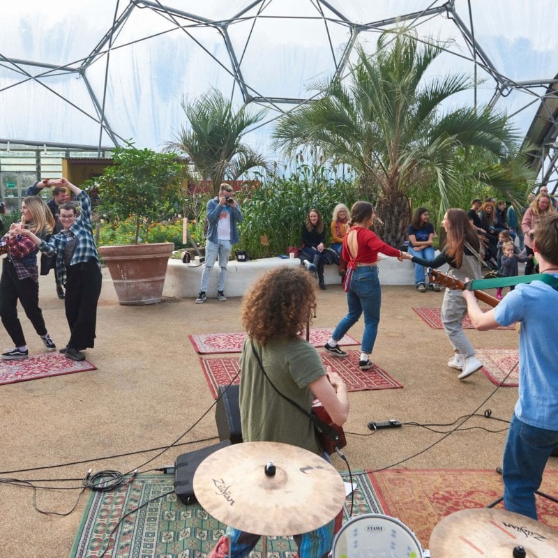 People dancing to a group of musicians playing in the Eden Project