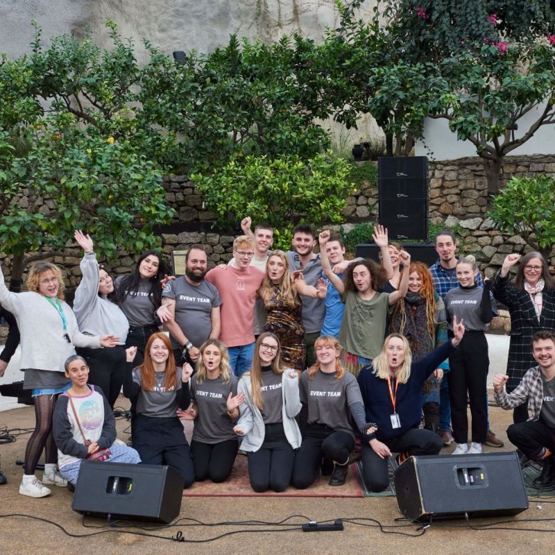 A large group of Sustainable Festival Management students posing in front of a wall with speakers on the floor