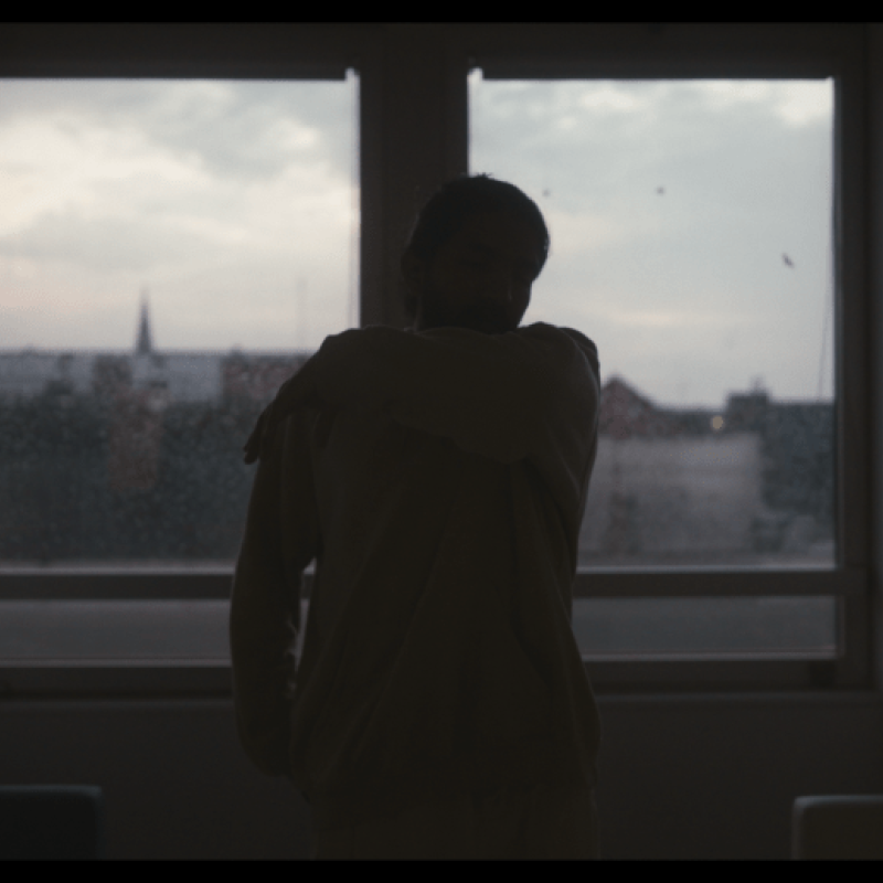The back of a man sat on a bed