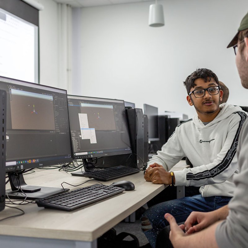 Students chatting to each other next to computers