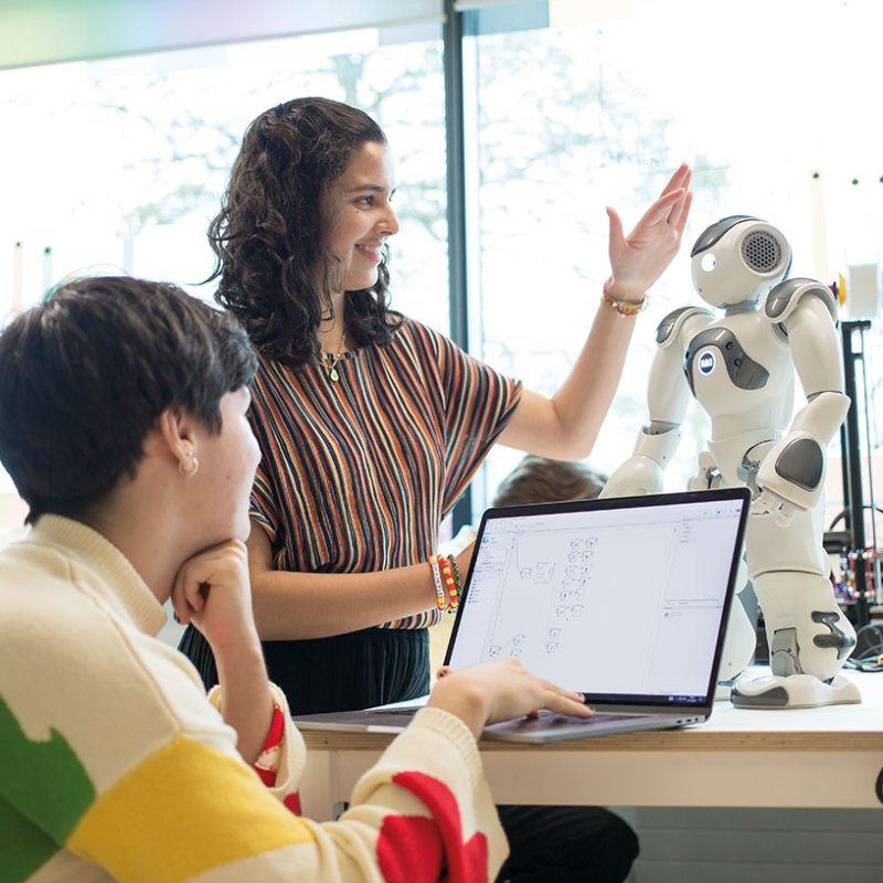 Robotics students discussing with robot on desk