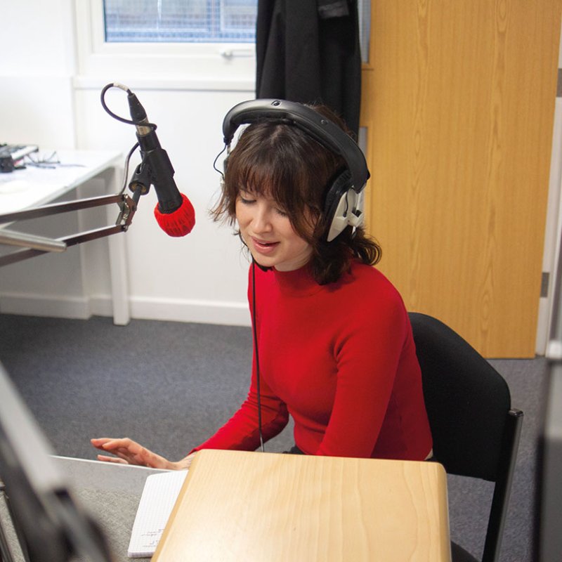 Students talking into microphone in sound studio