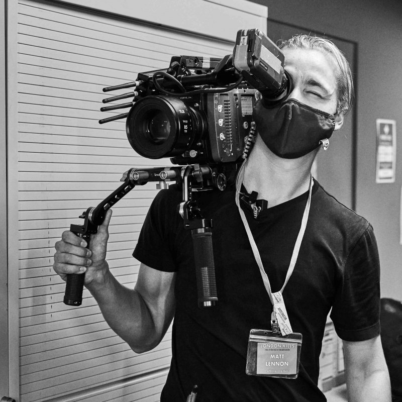 A masked student looks through a film camera