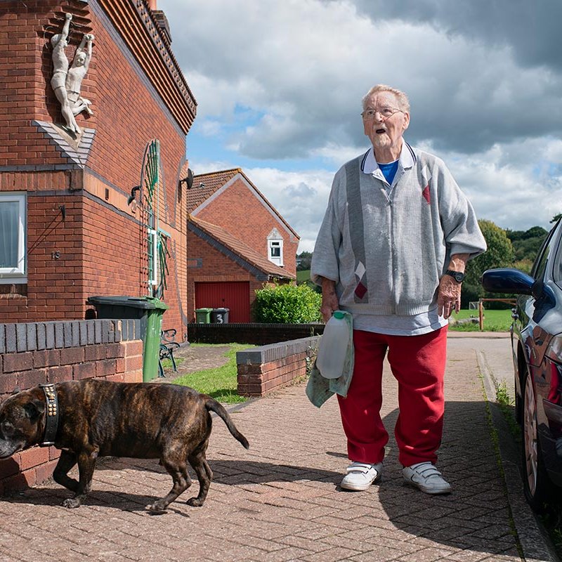 An elderly man and dog on a housing estate