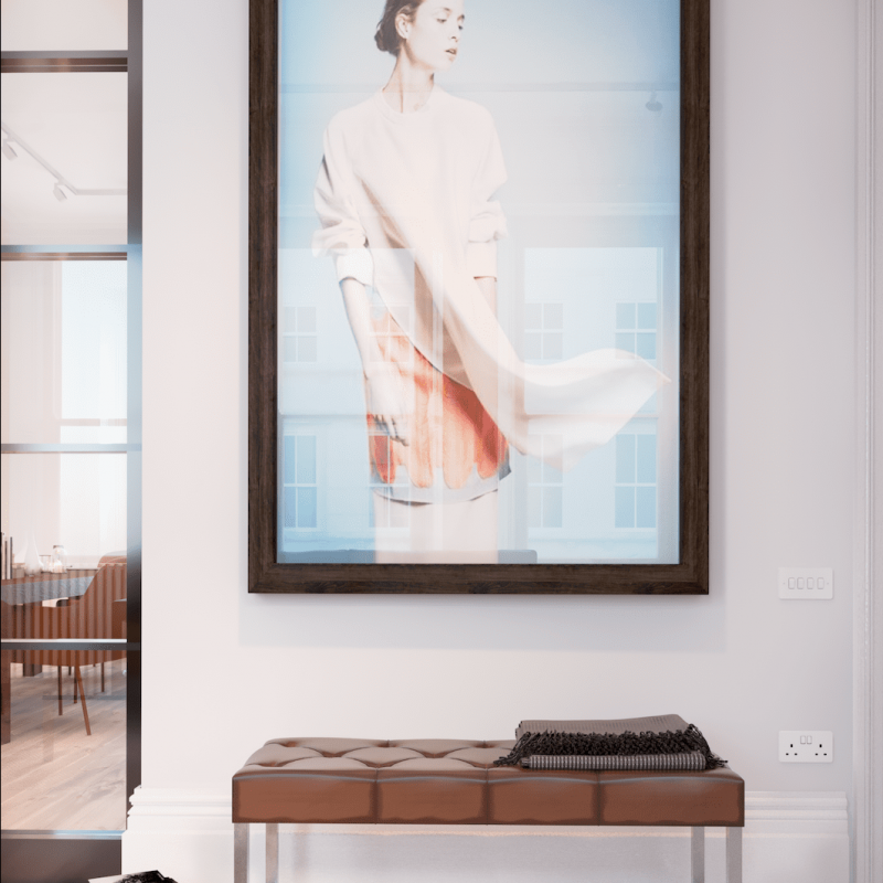 Large picture hung on a wall above a small bench. Picture is of a woman wearing white outfit blowing in the wind against blue background