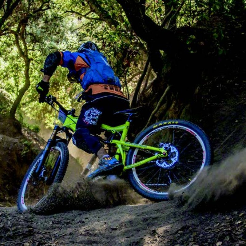 A person on a lime green mountain bike in the woods