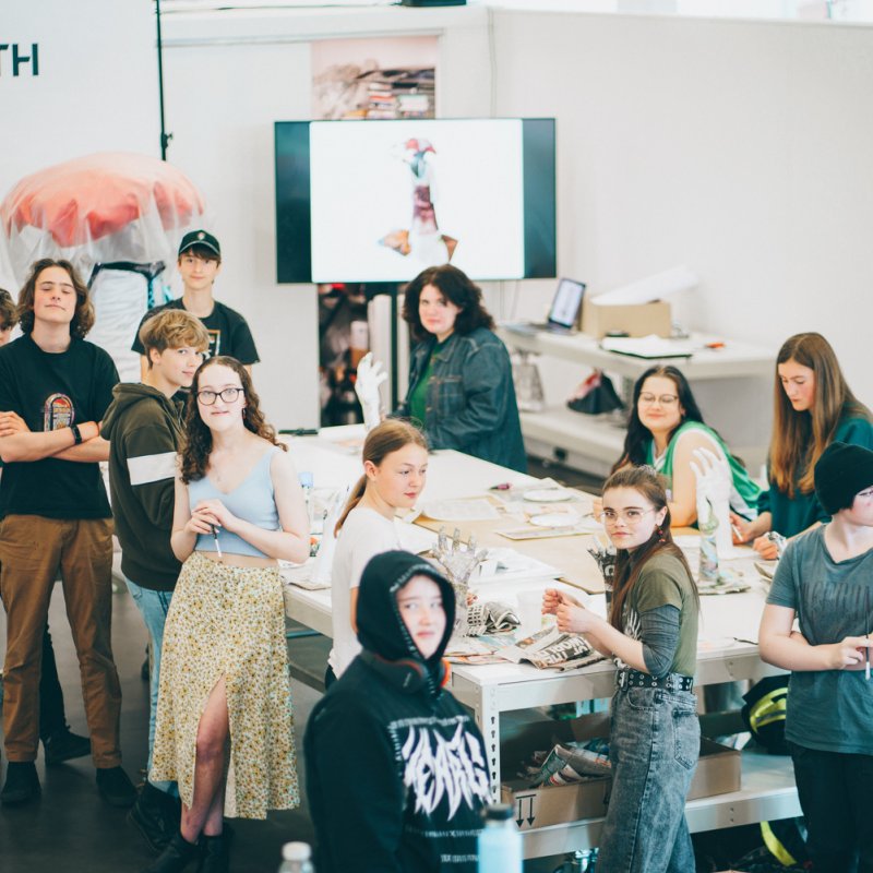 A group of young people making artworks on a large table