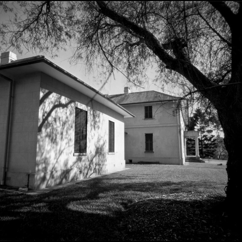 Black and white photograph of an old building with shutters on the windows