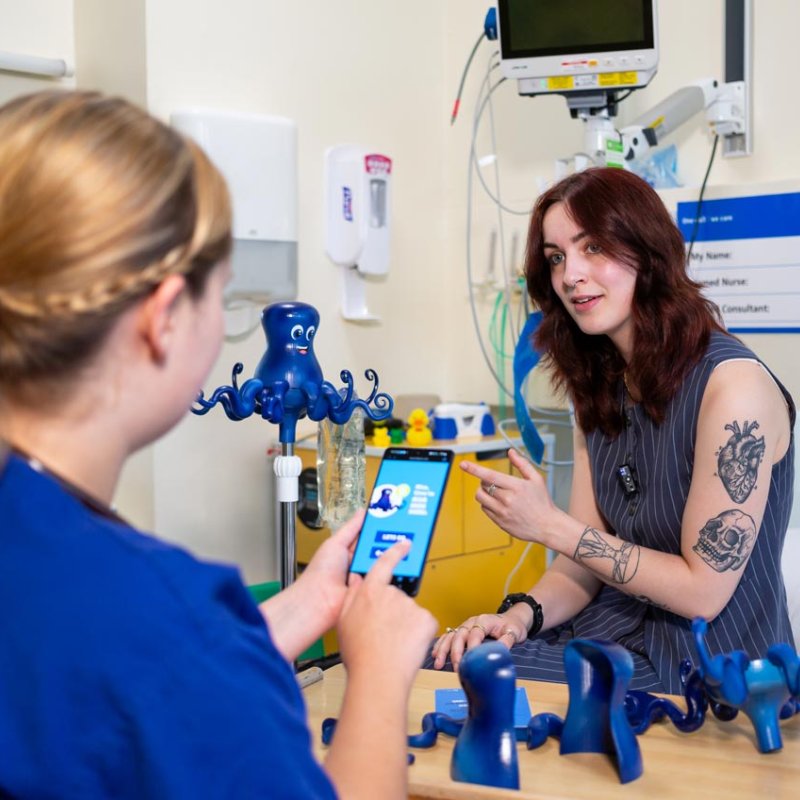 Falmouth University student, Florence Mitchell with a healthcare professional giving a demo of Olly the Octopus