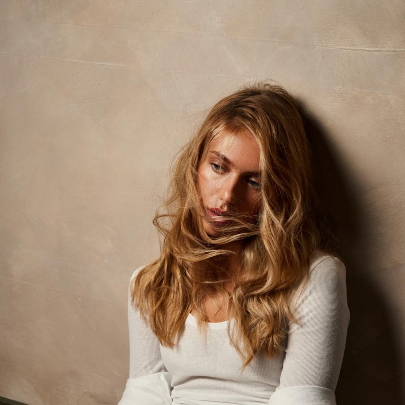 Photograph of a woman seated, with long blonde hair