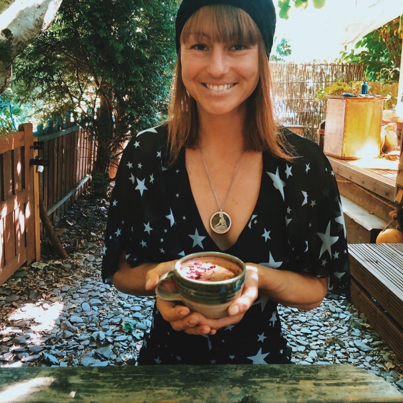 A woman wearing a black top with stars, holding a cup of coffee