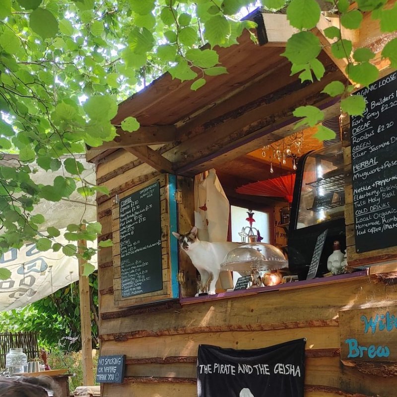 A wooden cafe front with a skull and cross bones and blackboard menus