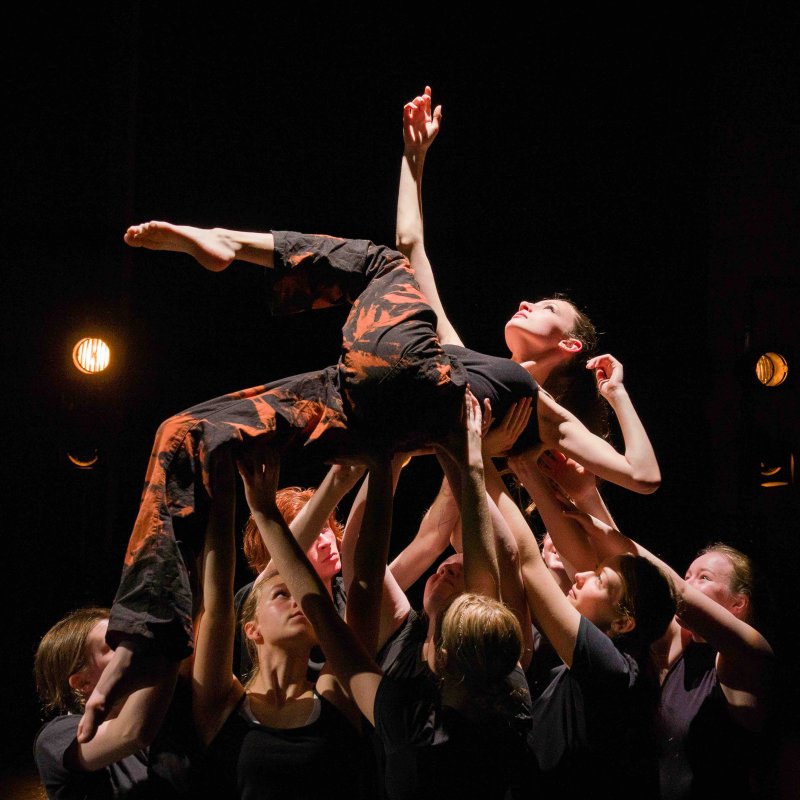 Group of dancers hold individual in air