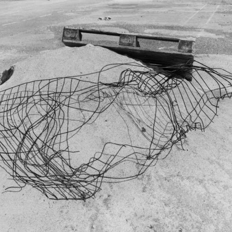 Broken wire and a wooden crate on a pile of sand