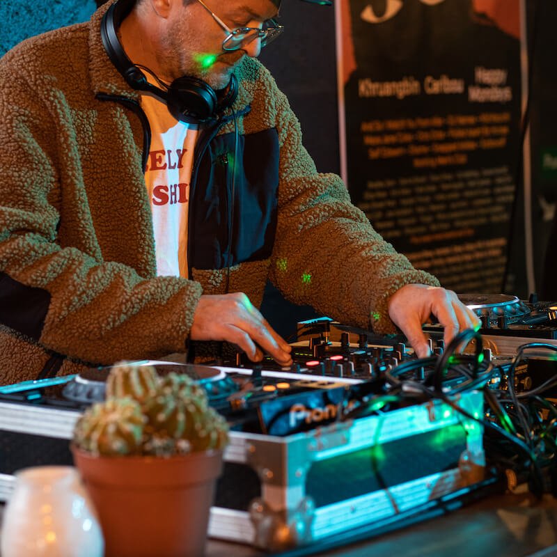 A man wearing a brown fleece djing at Verdant Taproom