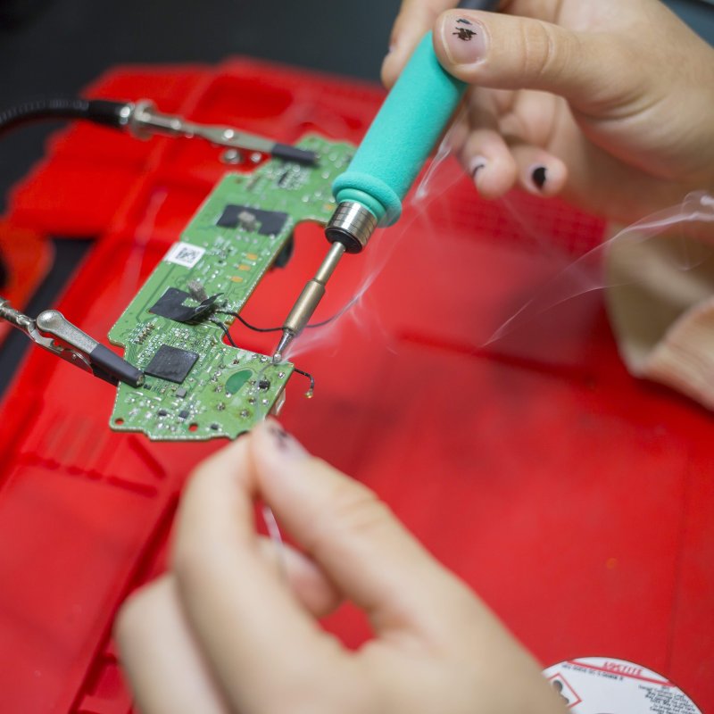 Robotics student soldering on computer board