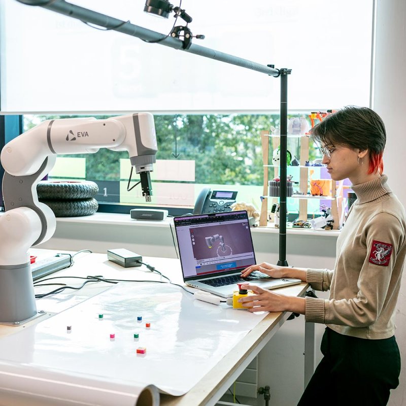 A Robotics student working with a laptop and robotic arm