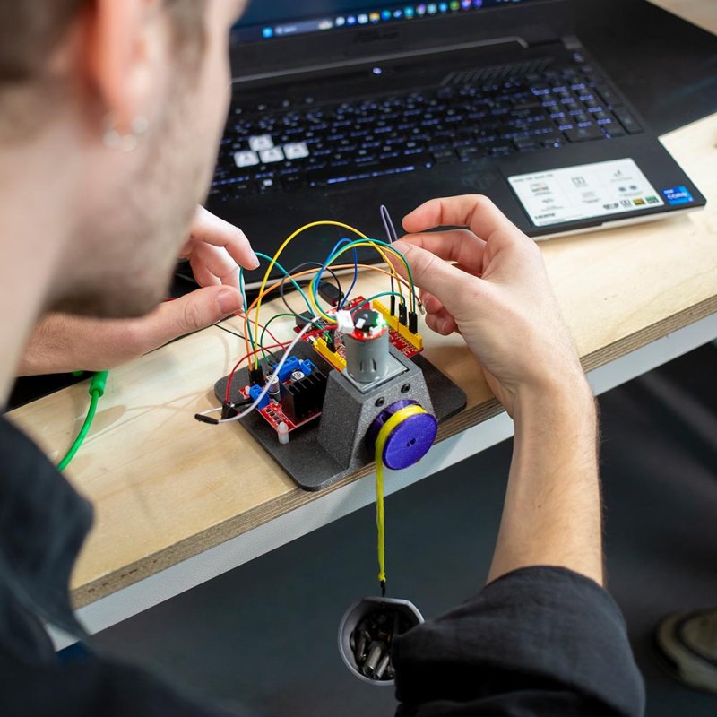A male Robotics student handling cables