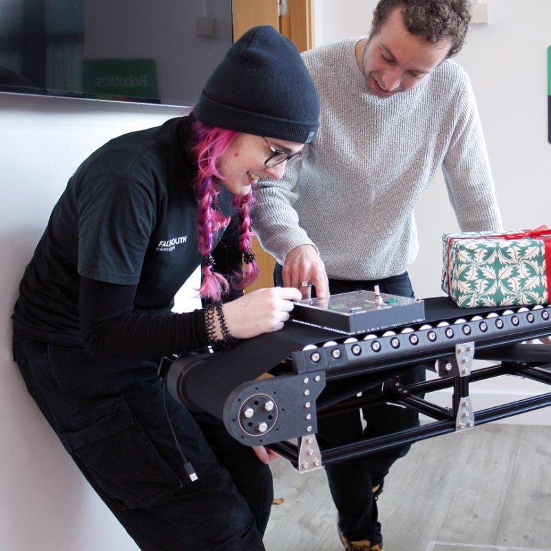 Two Robotics students working at a conveyer belt