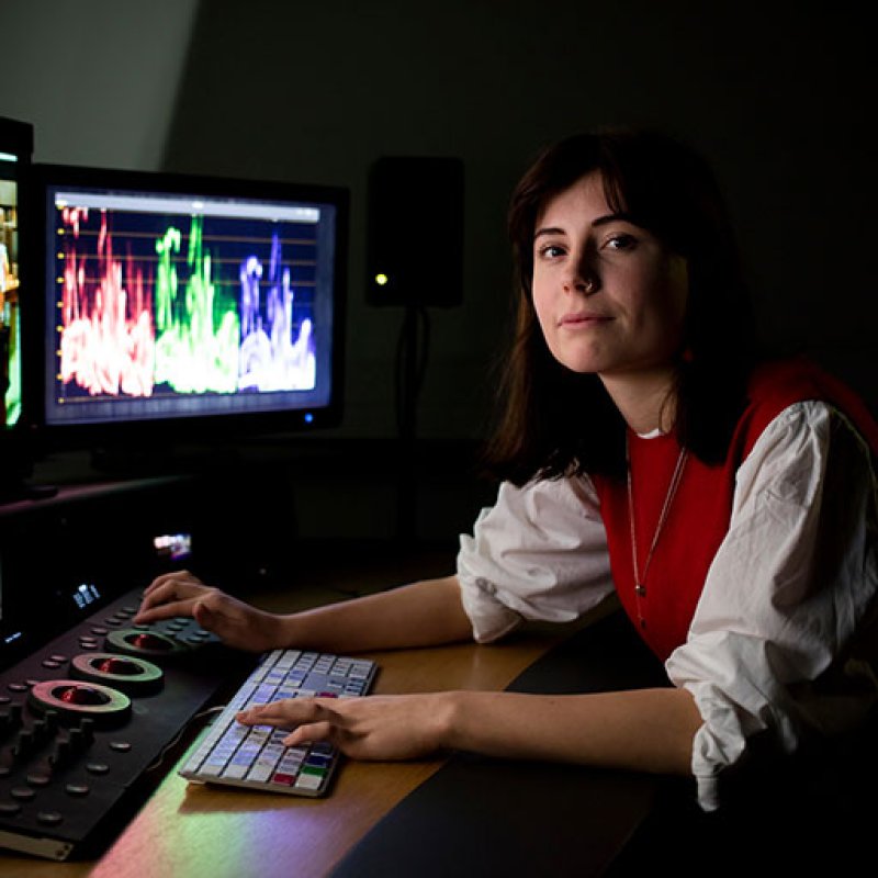 Student at editing desk with several screens in front of her.