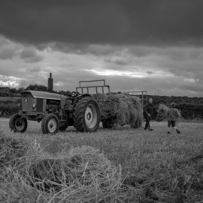 A man and boy loading hay onto a tractor