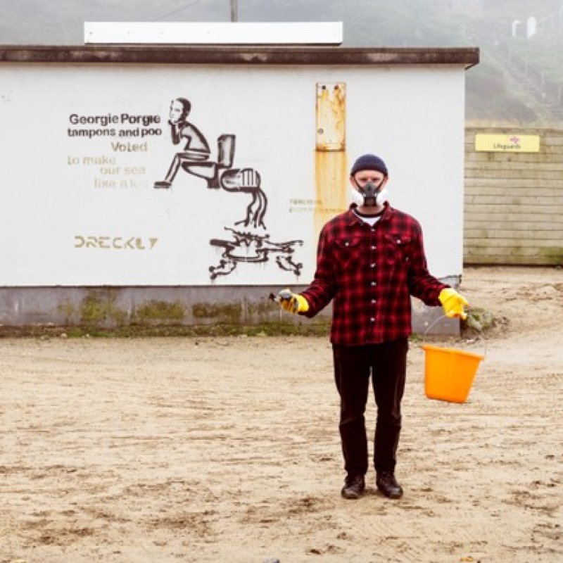 Sustainable Product Design graduate Niall Jones wearing mask and carrying a bucket on Porthtowan beach as part of SAS Floater campaign. 