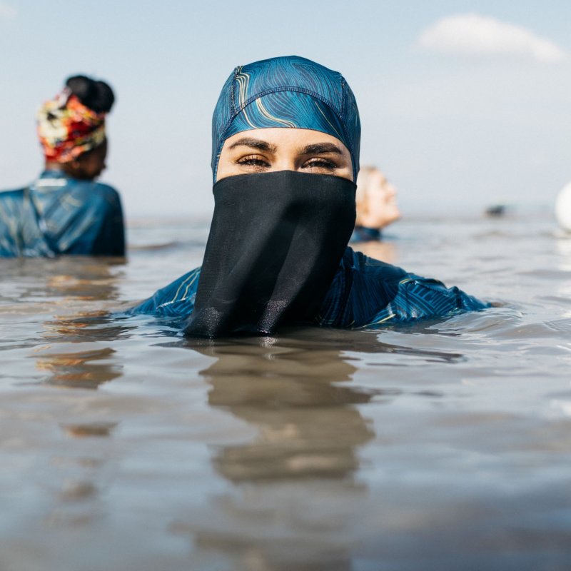 Women wearing Finisterre Hijab Seasuit, submerged in the sea up to shoulders