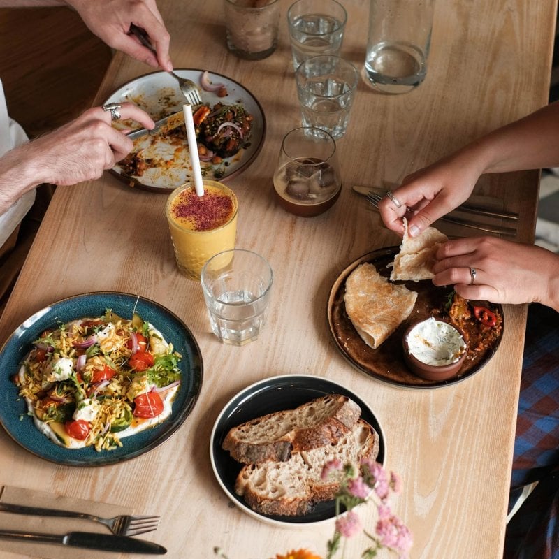 Cafe table with plates, drinks and hands