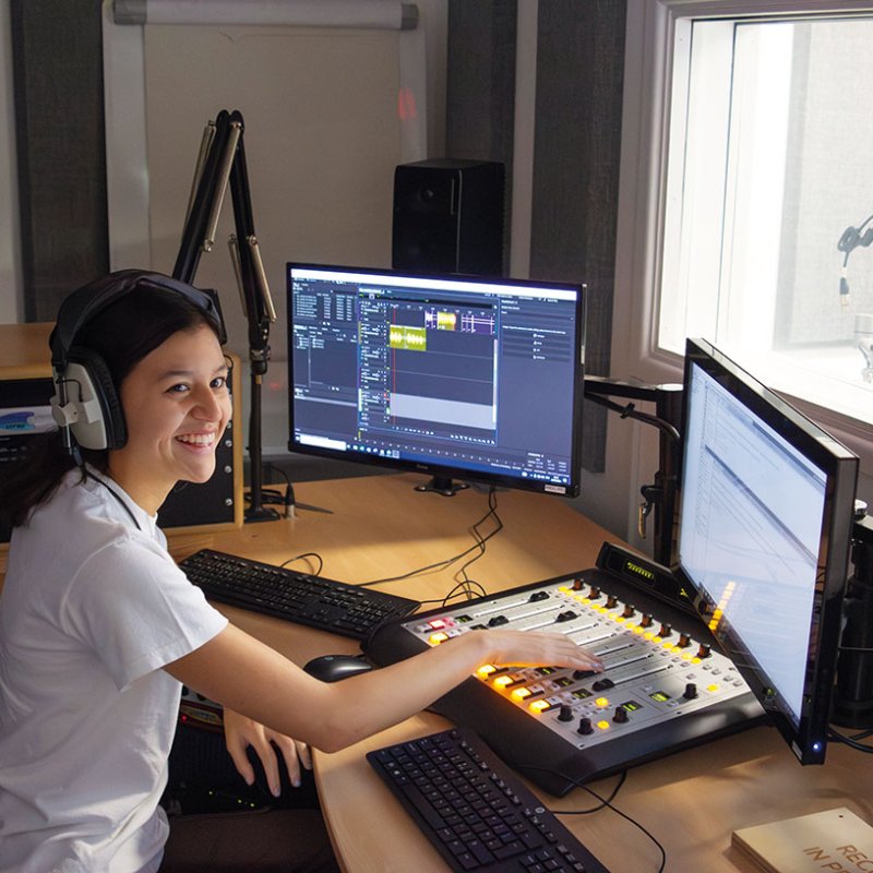 Student working at mixing desk with screens