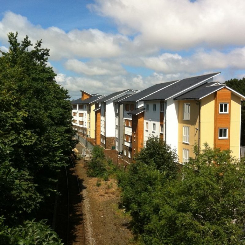 A building opposite train tracks and surrounded by trees 