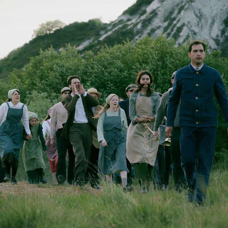 A group of people walking in the countryside dressed in 19th century dress