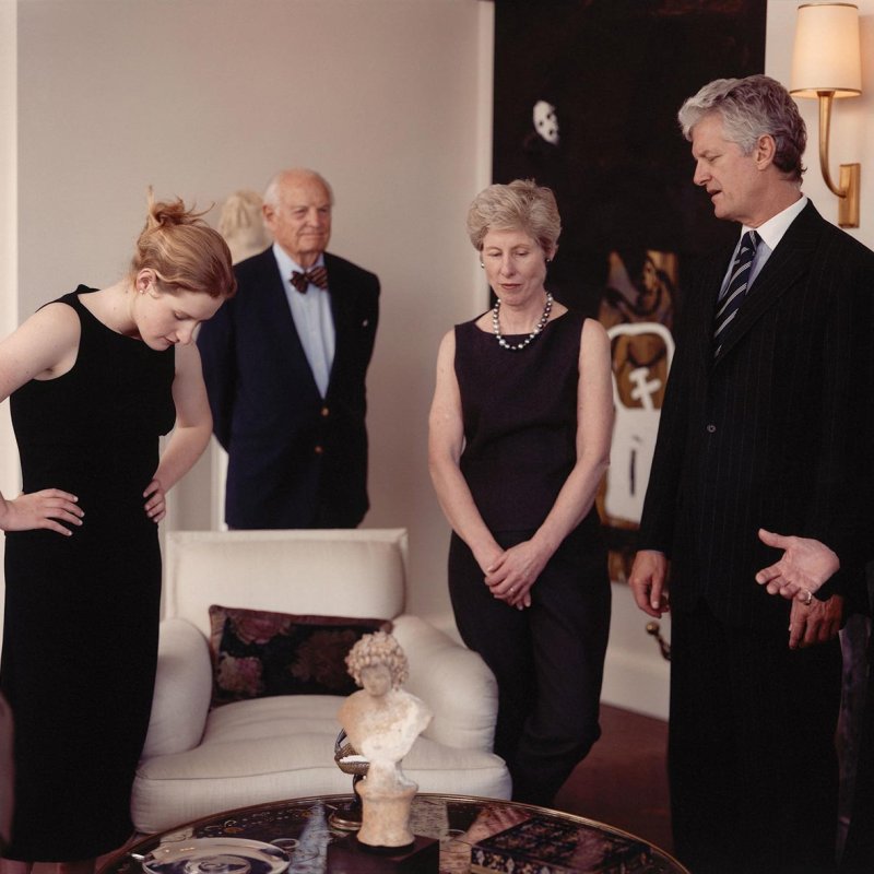 A well dressed family standing around a small table with a sculpture