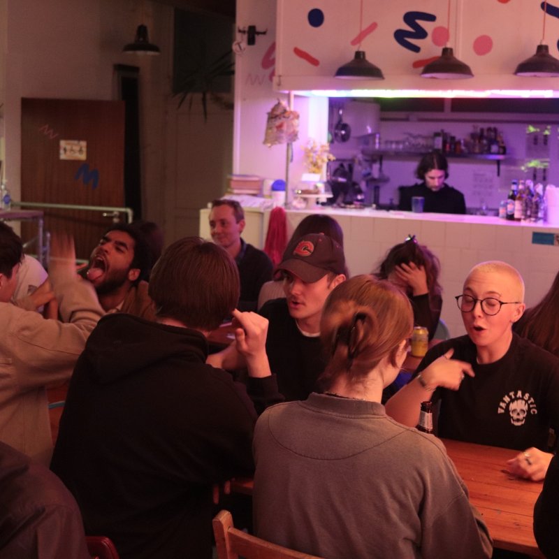 Groups of people sat around tables in a restaurant for a speed dating event