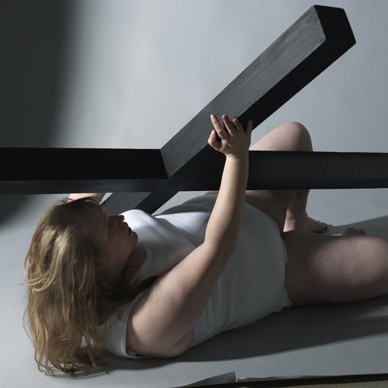 Woman lying on floor clutching wooden cross