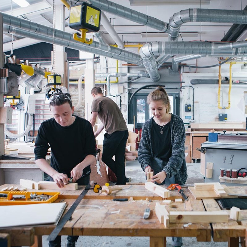 Female student and two male students in wood workshop