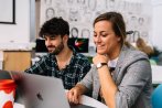 Two Falmouth University Creative Advertising students smiling at a laptop