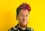 A person smiling into the camera against a yellow background