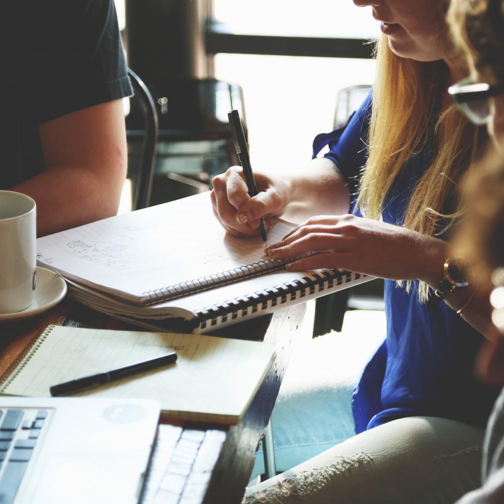 Business students sat around a desk, taking notes and drinking coffee.