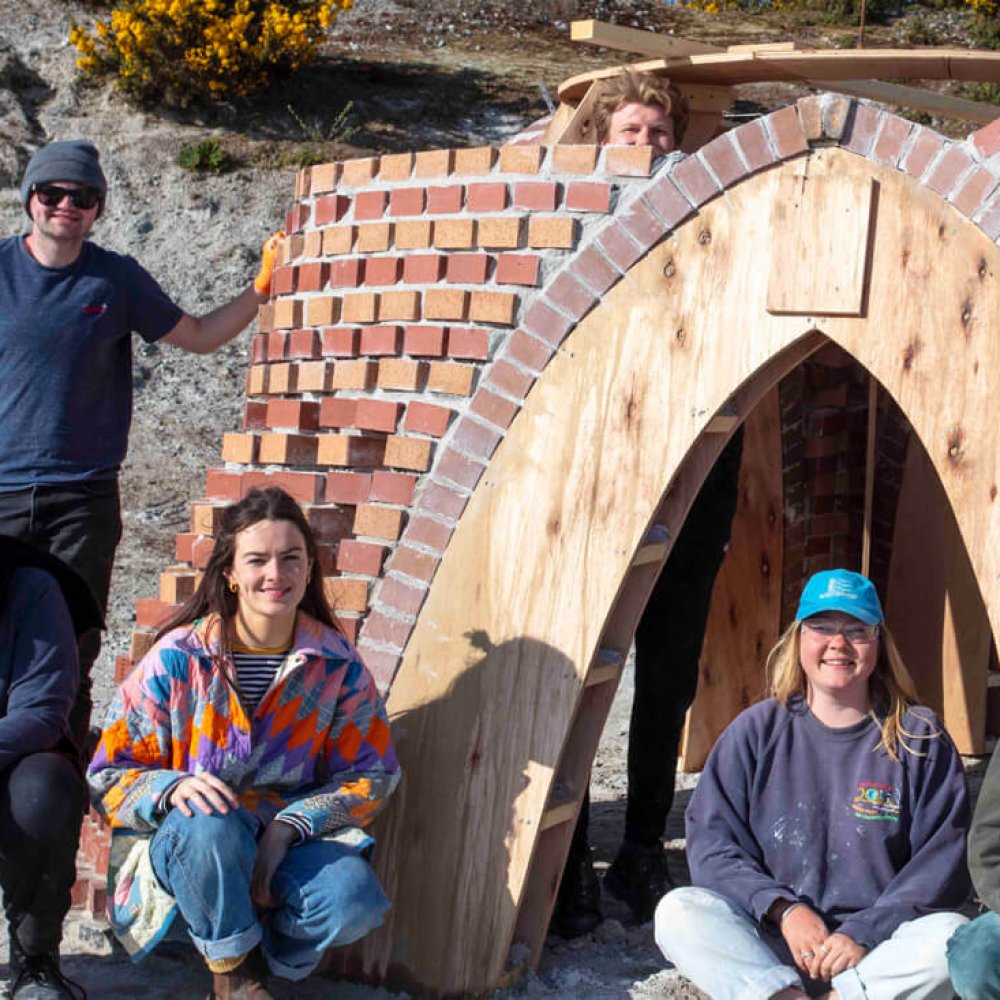 Architecture students outside a brick building with wooden arch