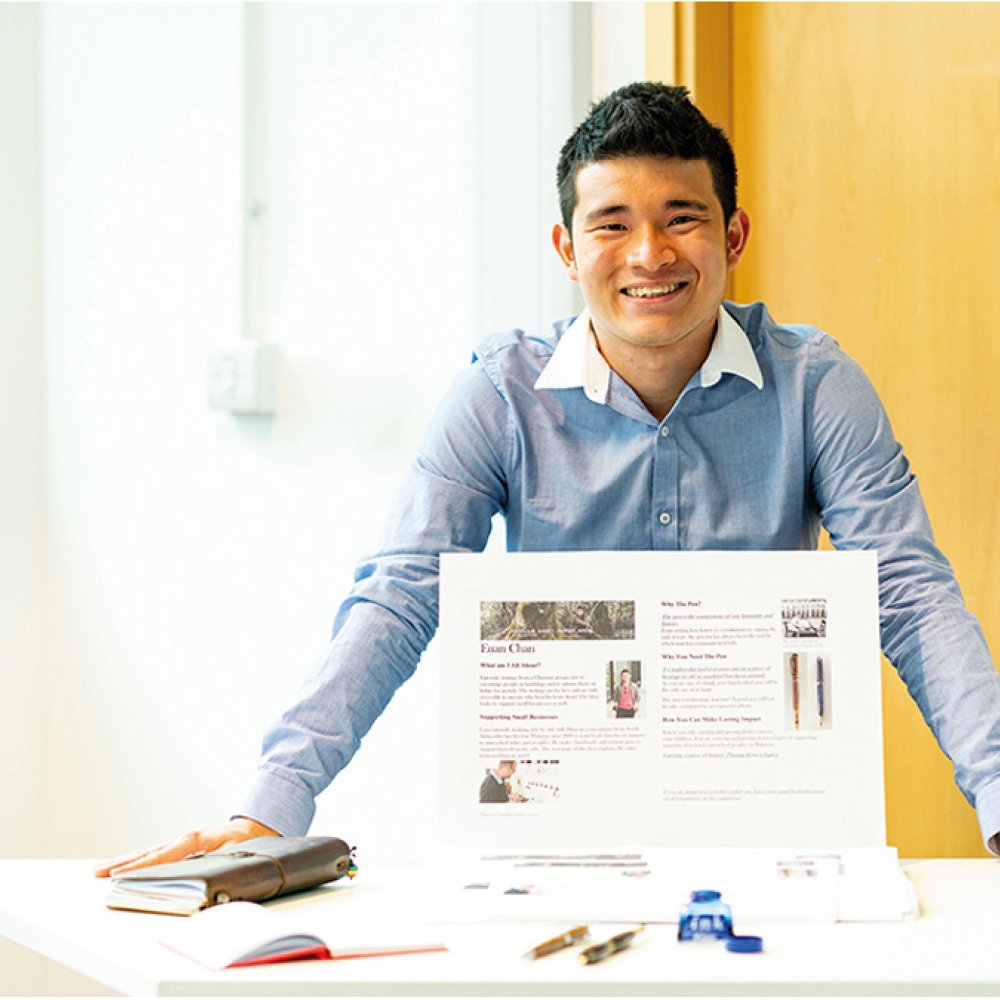 Business & Entrepreneurship student standing at a display table, smiling