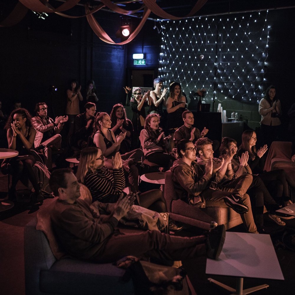 An audience sat around tables at an event