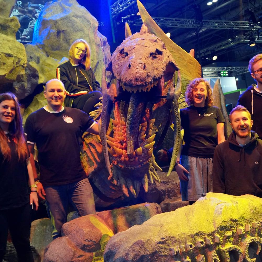 Falmouth University Games Academy students standing in front of a large dinosaur model