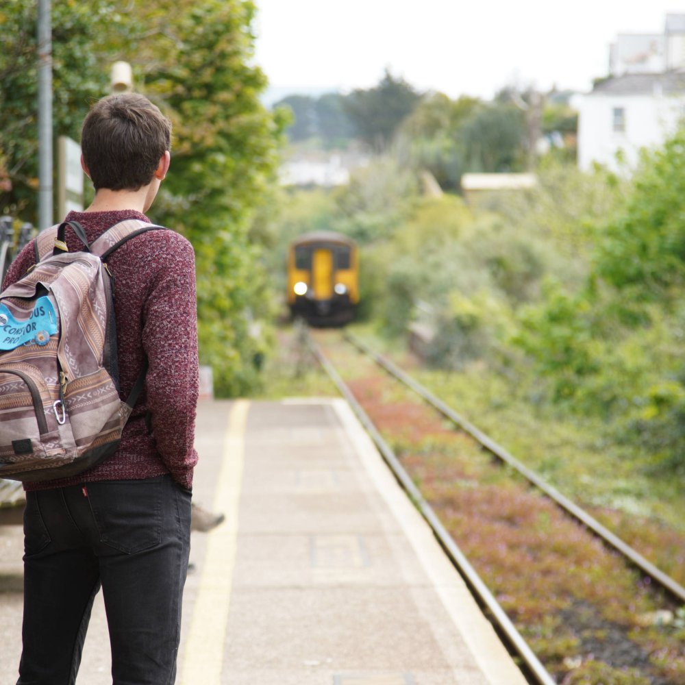 A man stands at a train station as a train approaches 